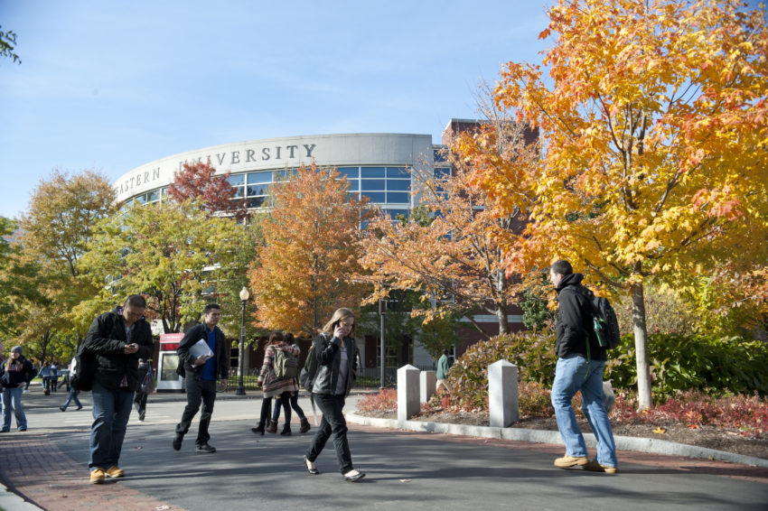 学生步行through campus on a fall day