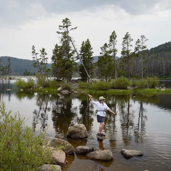 女人站在湖边的岩石上钓鱼