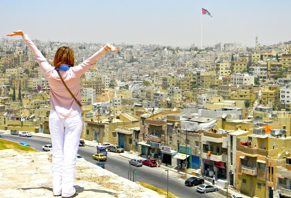 俯瞰城市的女人举起双臂。