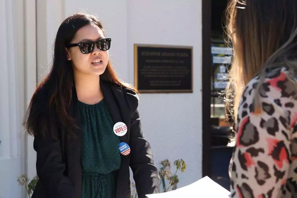 学生戴着墨镜和选民按钮与另一个学生在苏珊娜·亚当斯广场奥克兰东北大学的校园raybet雷竞技雷竞技app最新版