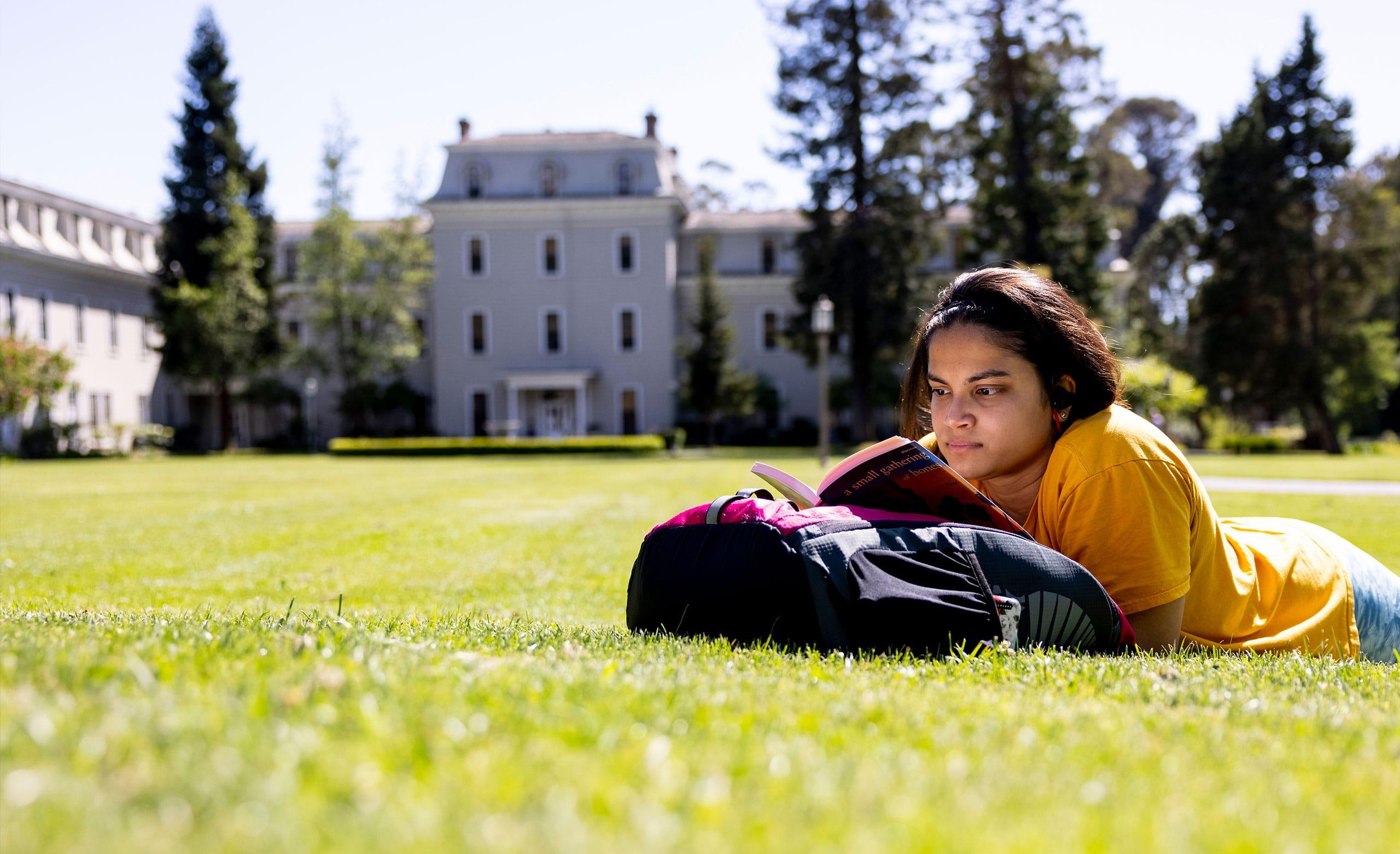 学生躺在霍姆格伦草地的草地上看书，远处是米尔斯大厅。