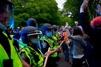 穿黄背心和头盔的警察封锁抗议者