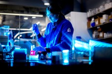 穿蓝实验大衣和护目镜者在实验室内用测试管工作