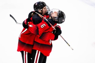 东北曲棍球选手在哈佛获选Women's Beanpot半决赛后在冰场相互拥抱