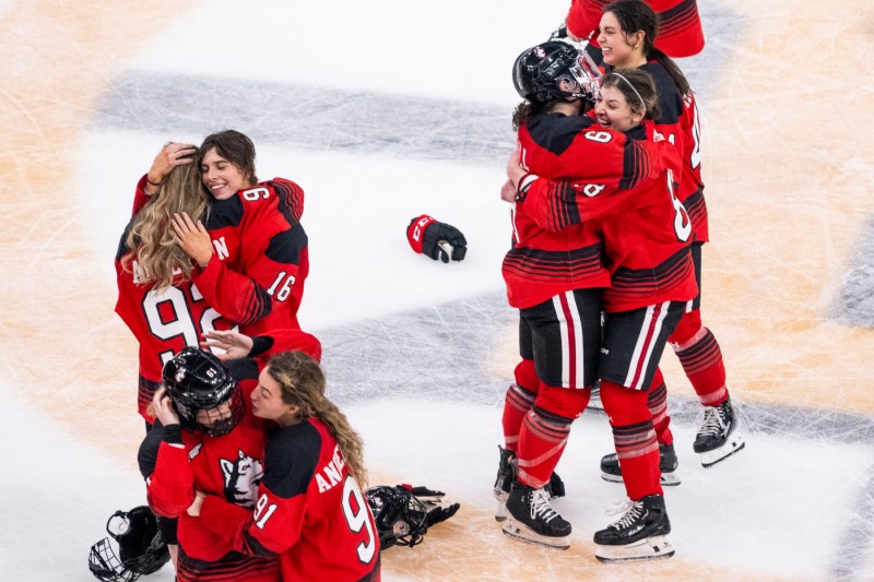 东北女子曲棍球队成员在赢得Beanpot后在冰上相互拥抱