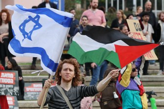 人群中一人手持以色列国旗,另一人手持巴勒斯坦国旗