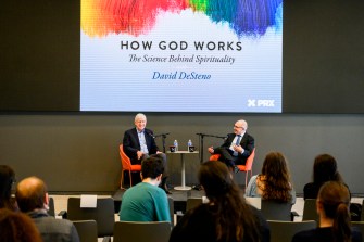 Dave Desteno和Francis Collins在屏幕前用麦克风说话,屏幕上写着“上帝如何工作”。