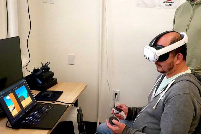 一个人从笔记本电脑上坐着, 穿VR耳机并玩游戏