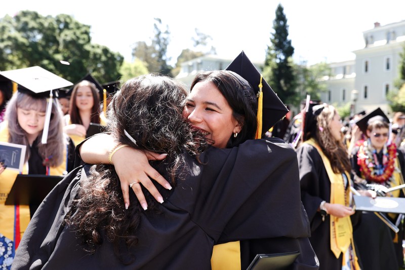 两位毕业生在东北Oakland启动时相互拥抱