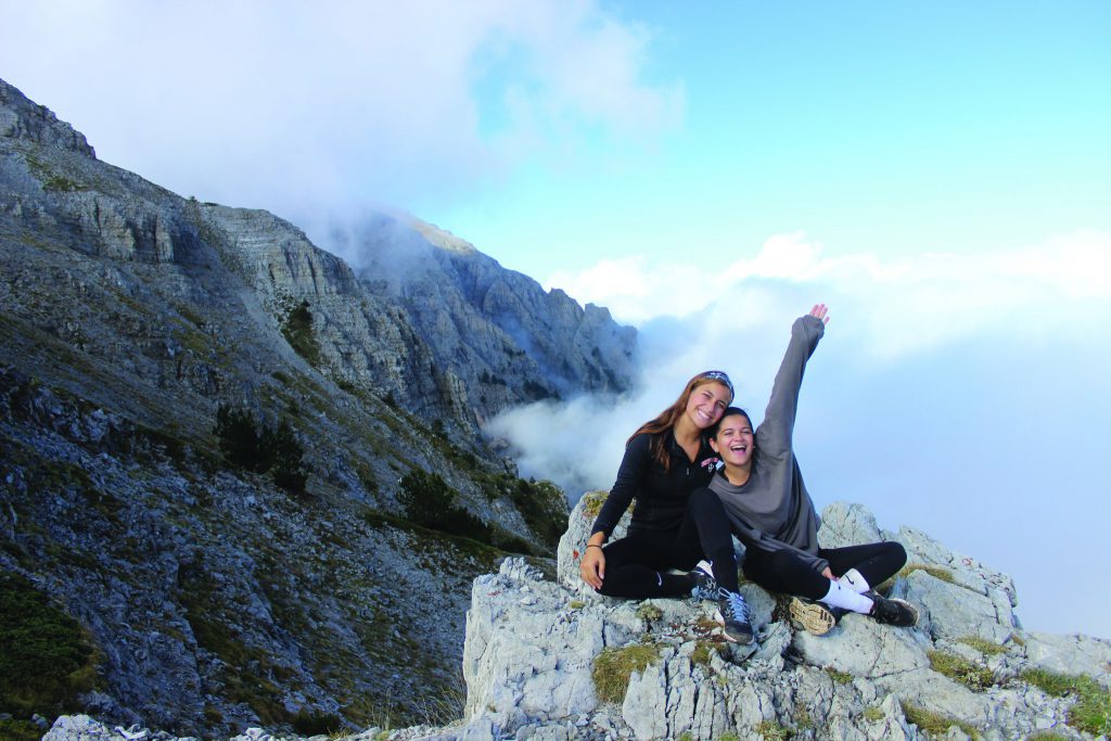 两个学生坐在一个大岩石山的顶部。他们正在微笑