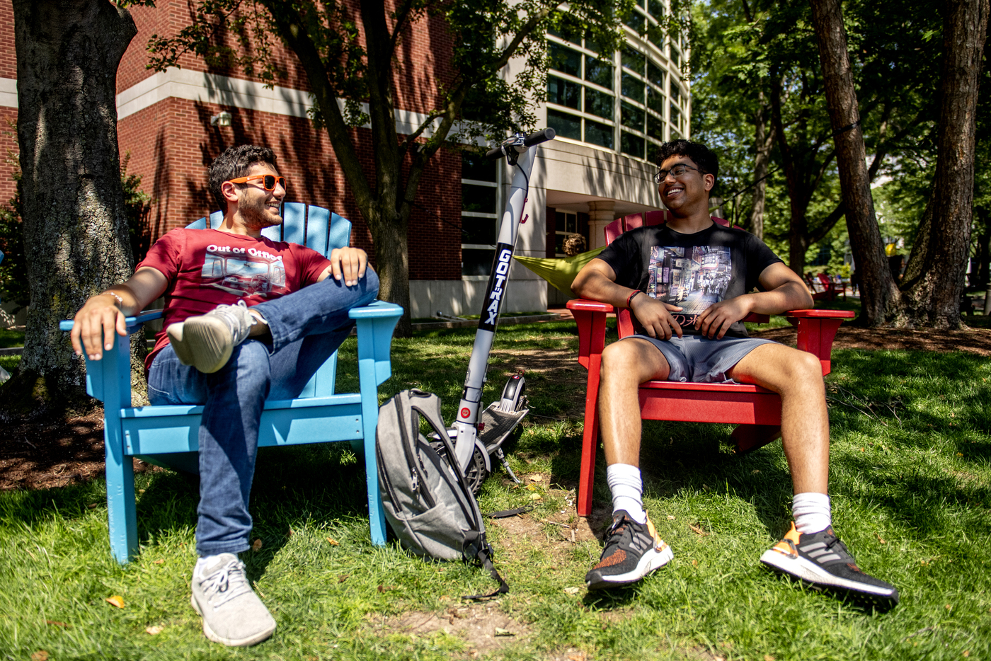 两个学生聊天,笑着坐在草坪的椅子